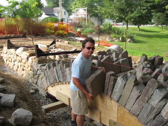 Greg Wheeler fits another stone into place at the MacDougall bridge workshop